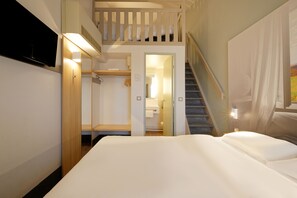 Una habitación de hotel con una cama, una escalera y un baño visible a través de una puerta abierta.
