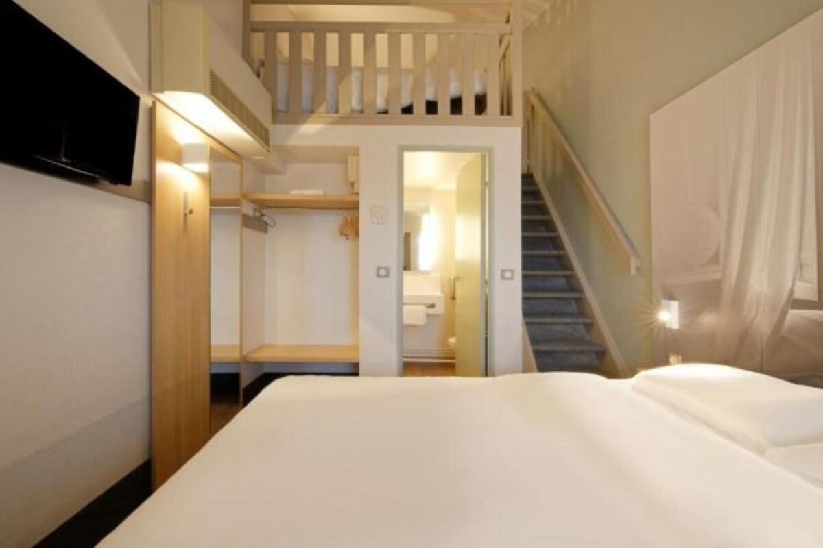 A bedroom with a bed, a staircase, and a closet.