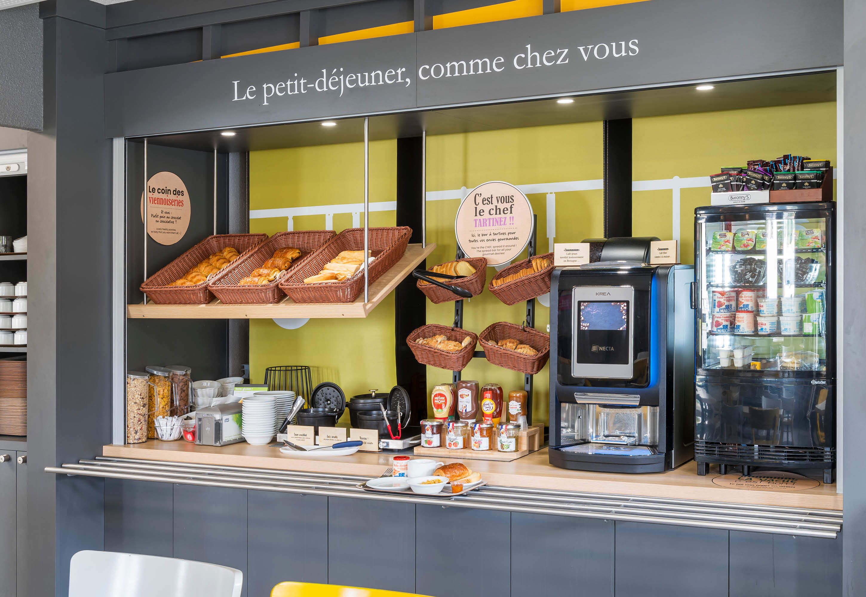 A breakfast counter with wicker baskets of bread, condiments, and a coffee machine.