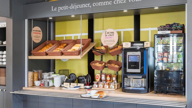 Una barra de desayuno con cesteras de mimbre llenas de pan, condimentos y una máquina de café.
