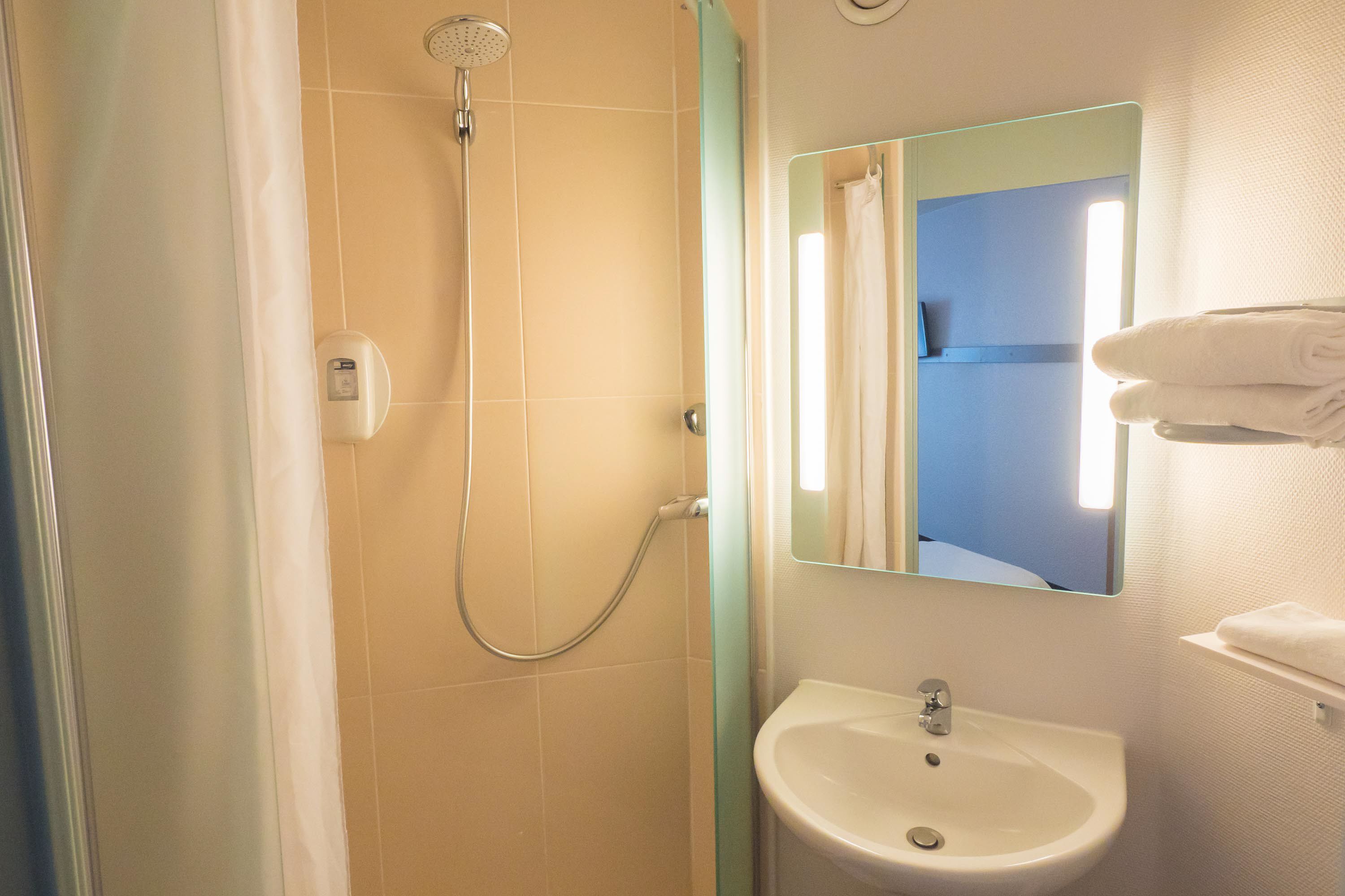 A bathroom with a shower, sink, and a mirror.