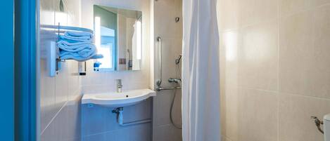 Un baño moderno con lavamanos, espejo y ducha.