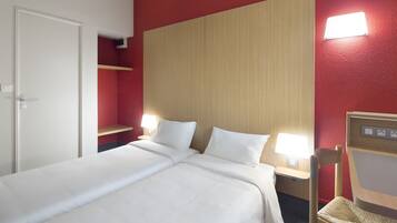 A hotel room with a bed, two bedside tables, a chair, and a wardrobe.