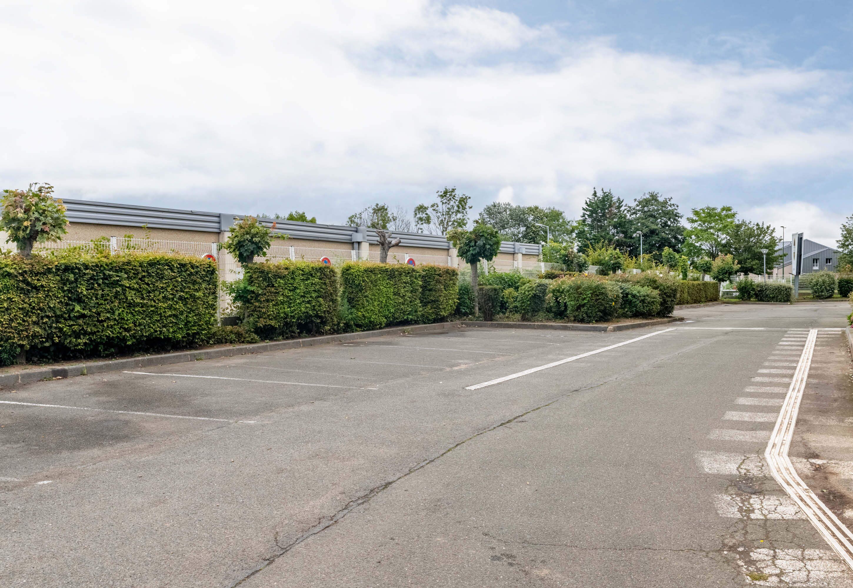 A quiet street with a row of buildings, a parking lot, and a pedestrian crossing.