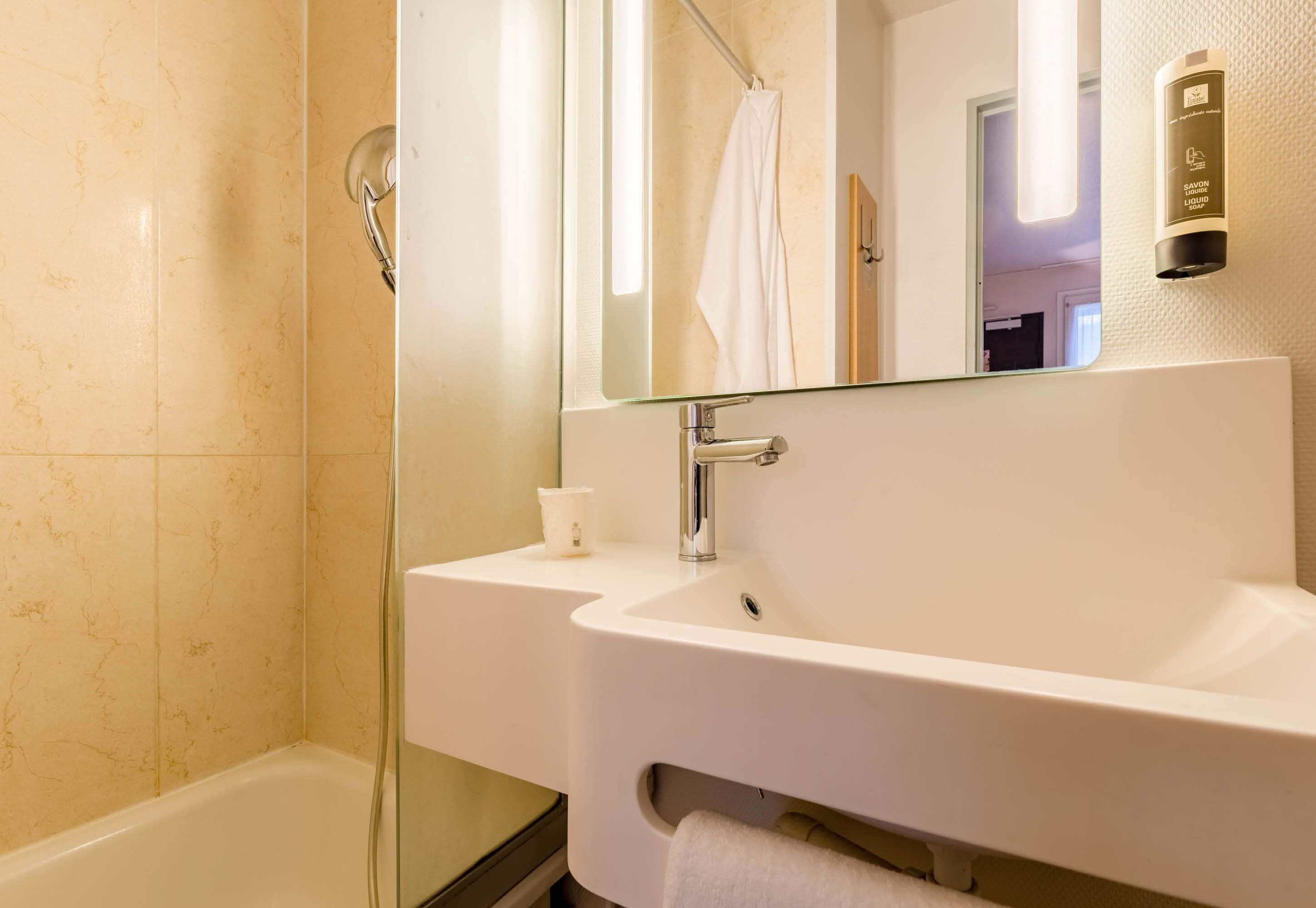 A modern bathroom with a glass shower enclosure, a white sink, and a large mirror.