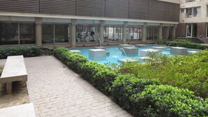 A modern building with a rooftop pool area, surrounded by greenery and featuring large windows and balconies. - Alojamientos Santiago Chile (Santiago)