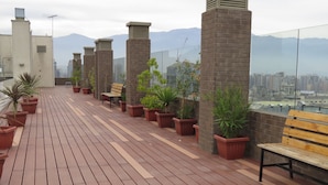 A rooftop terrace with wooden flooring, potted plants, and benches. - Alojamientos Santiago Chile (Santiago)