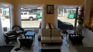 A hotel lobby with a sofa, chairs, a coffee table, and a view of the street outside. - Hotel Italia (La Ceiba)