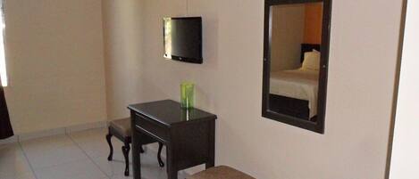A hotel room with a bed, a TV, a desk, and a chair.