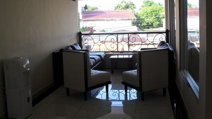 A balcony with a metal railing, a water dispenser, and two cushioned chairs. - Hotel Italia (La Ceiba)