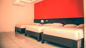 A hotel room with two beds, a red accent wall, a ceiling light, and an air conditioning unit. - Hotel Italia (La Ceiba)