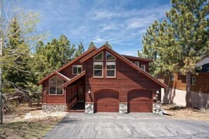 A two-story wooden house with a steeply pitched roof, a front porch, and a garage. - Wolfgang Family Retreat (Truckee)
