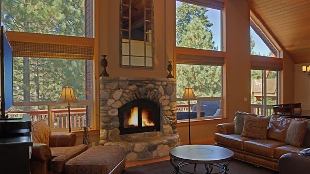 Una sala de estar acogedora con chimenea de piedra, ventanas amplias y asientos cómodos.