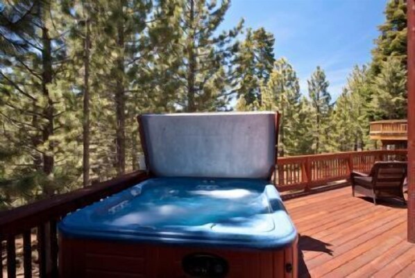 Un bain à remous sur une terrasse en bois, entouré d’arbres.