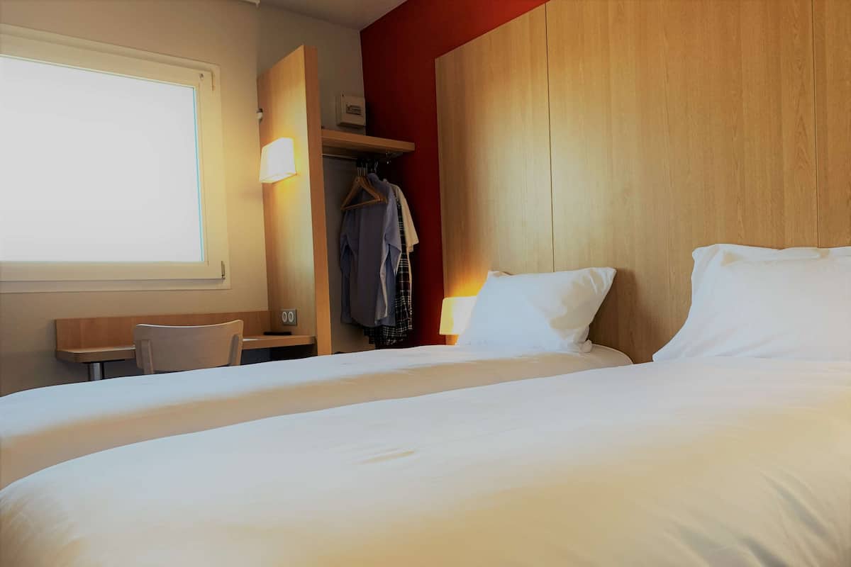Een hotelkamer met een groot bed, een bureau, een stoel, een kledingkast en een raam.