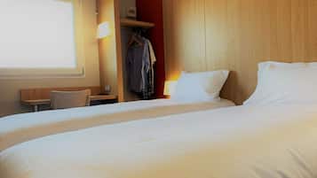 Een hotelkamer met een groot bed, een bureau, een stoel, een kledingkast en een raam.