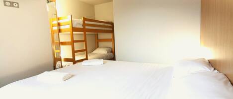 A room with bunk beds, a flat-screen TV, and a ceiling air conditioning unit.
