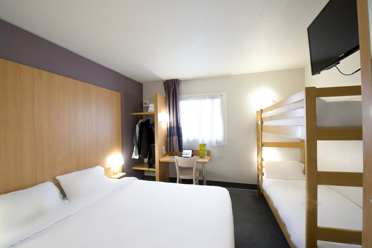 Een hotelkamer met een bed, een bureau, een stoel, een televisie en een kledingkast.
