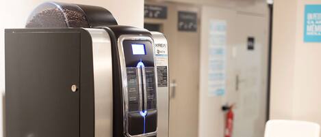 A coffee machine with a digital display, a cup holder, and a tray with cups and a bowl.
