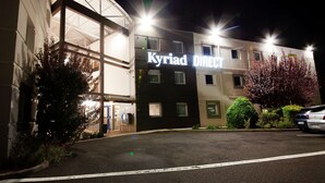 A hotel named 'Kyriad DIRECT' with a modern architectural design, featuring a glass facade and a parking area in front. - Kyriad Direct Clermont Ferrand Nord - Gerzat (Gerzat)