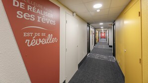 A hotel hallway with a red and white wall featuring motivational text. - B&B HOTEL Poitiers (1) (Chasseneuil-du-Poitou)