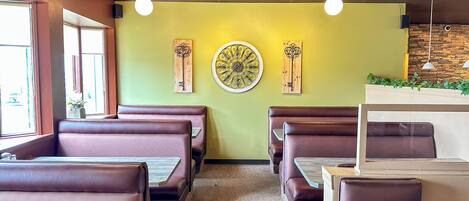 A restaurant interior with booths and tables, green walls, and decorative wall art.