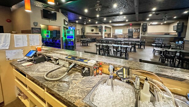 Un restaurante con mostrador de mármol, cubiteras y una zona de estar con mesas y sillas.