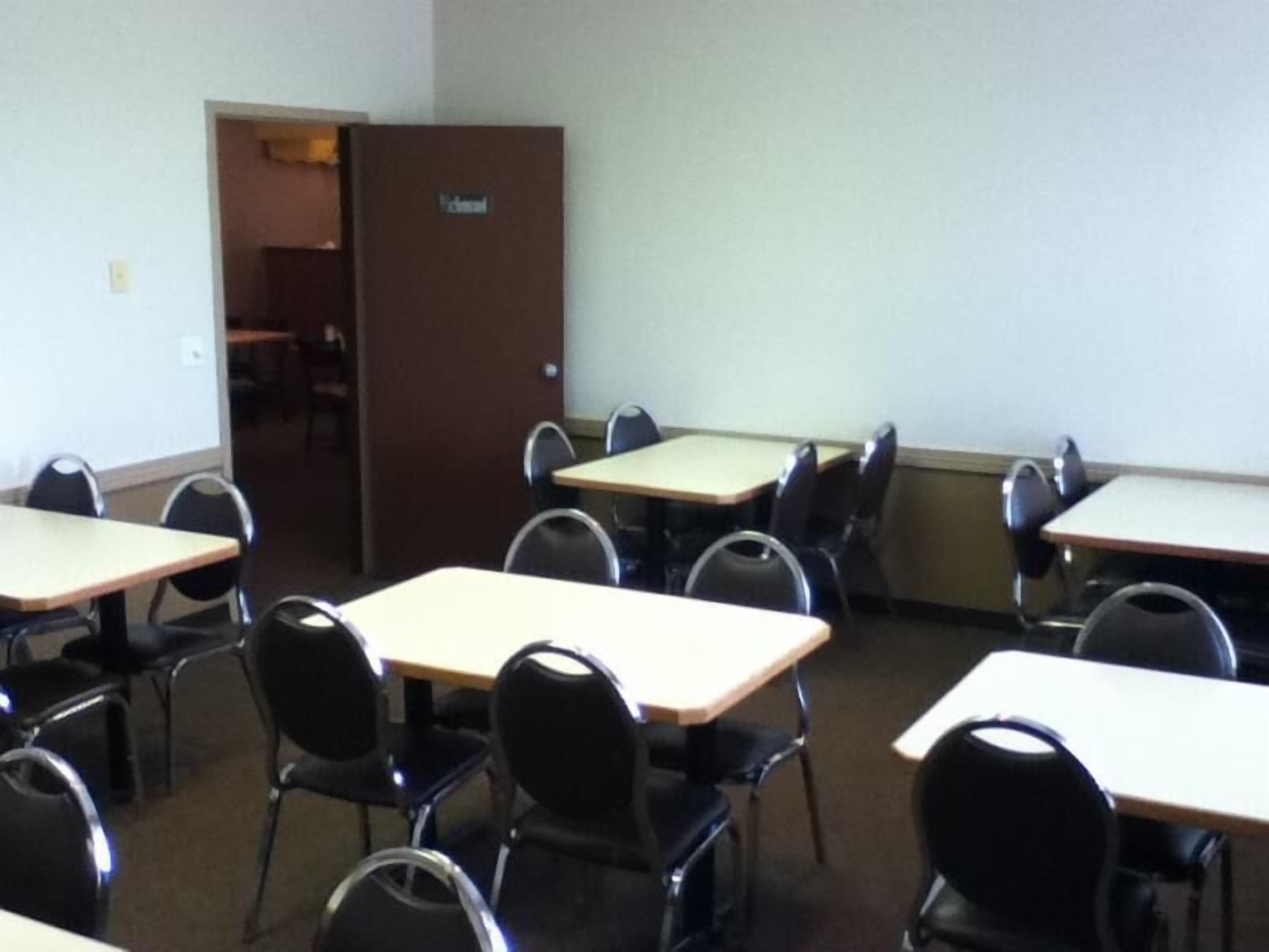 A classroom with multiple tables and chairs, a whiteboard, and a door labeled "Office".