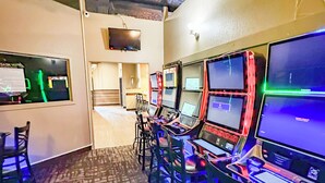 Una sala de juegos con varias estaciones de juego, un televisor y suelo alfombrado.