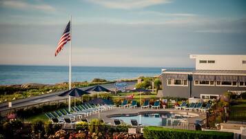 A hotel with a pool, sun loungers, and a view of the ocean.