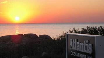 A sunset view with a sign for 'Atlantis Oceanfront Inn'.
