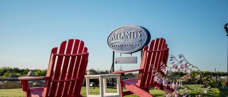 Two red Adirondack chairs, a sign for 'Atlantis Oceanfront Inn', and a 'Breakfast Cafe' sign.