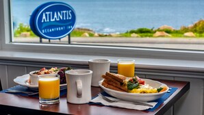Ein Frühstückstisch mit Blick auf den Ozean und einem Schild mit der Aufschrift 'ATLANTIS'.