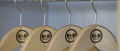 Cuatro perchas de madera con el logotipo "B&B Hotels" sobre un perchero metálico.