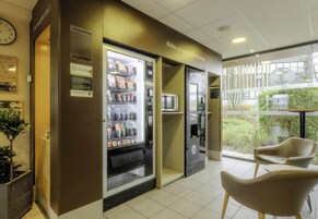 Zona de máquinas expendedoras con aperitivos y un microondas. Hay dos sillas y una pequeña mesa.