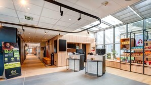 Un interior moderno con una recepción, detalles de madera y un amplio ventanal que proporciona luz natural.