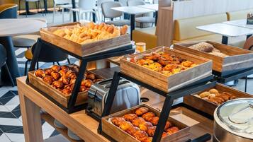 A buffet setup with various baked goods and a toaster.