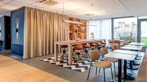 Un comedor moderno con una mesa larga, varias sillas y una estantería.