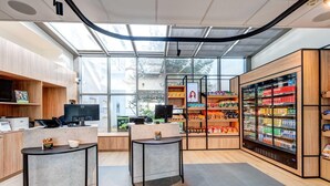 Una tienda moderna, bien iluminada, con techo de vidrio, estanterías de madera y una sección refrigerada.