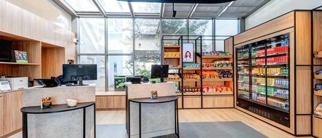 Una tienda moderna, bien iluminada, con techo de vidrio, estanterías de madera y una sección refrigerada.