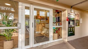 A hotel entrance with a glass door, a reception desk, a plant, and a vending machine. - B&B HOTEL Brest Kergaradec (Gouesnou)