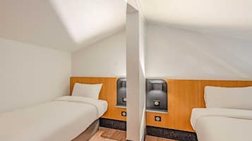 Een hotelkamer met twee bedden, houten hoofdeinden en een zithoekje met een tafel en stoelen.