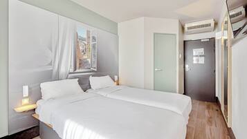 Un dormitorio moderno con cama, mesitas de noche, una ventana con cortinas, una puerta y un equipo de aire acondicionado.