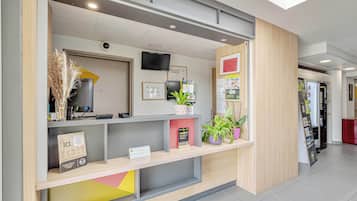 A reception area with a counter, a television, framed certificates, and potted plants.