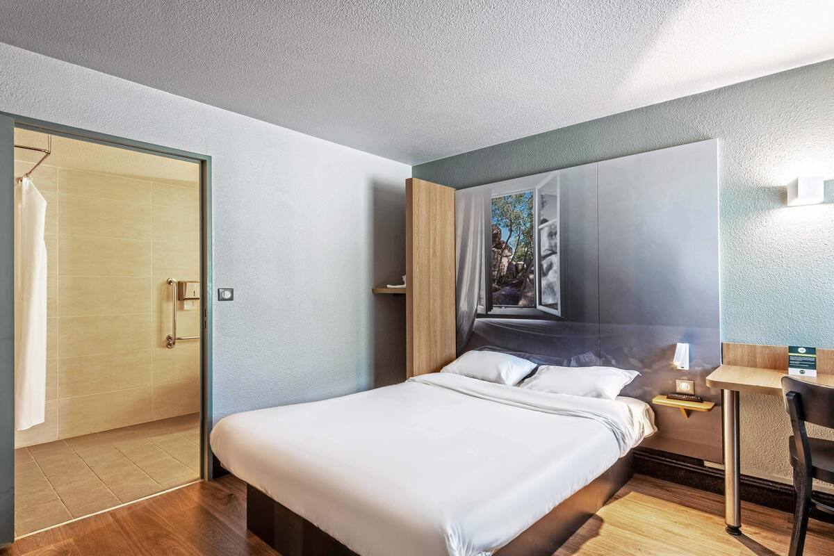 Une chambre d’hôtel moderne dotée d’un grand lit, d’un bureau et d’un espace douche.