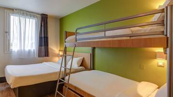 A bunk bed room with a window, curtains, and a bedside lamp.