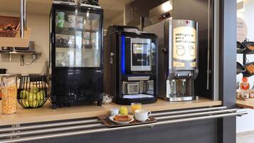 A breakfast bar with a coffee machine, a refrigerator, and a basket of fresh fruits.
