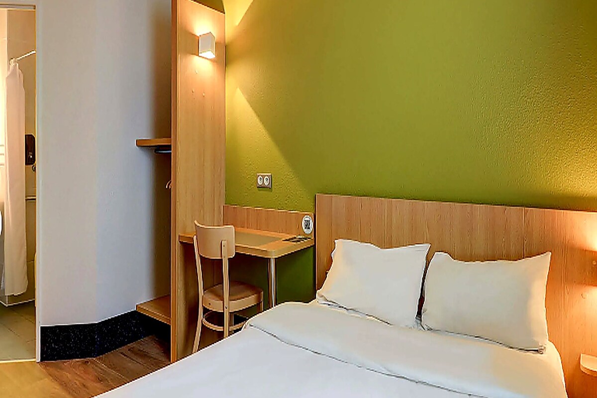 Een hotelkamer met een bed, een bureau en een stoel.