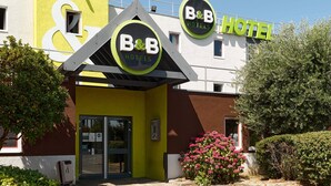 Een bed en breakfast hotel met een opvallende gele gevel, een groot 'B&B'-bord en een 'HOTEL'-bord boven de ingang.