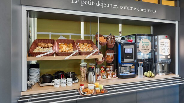 Een ontbijtbuffet met brood, gebak en koffieautomaten.